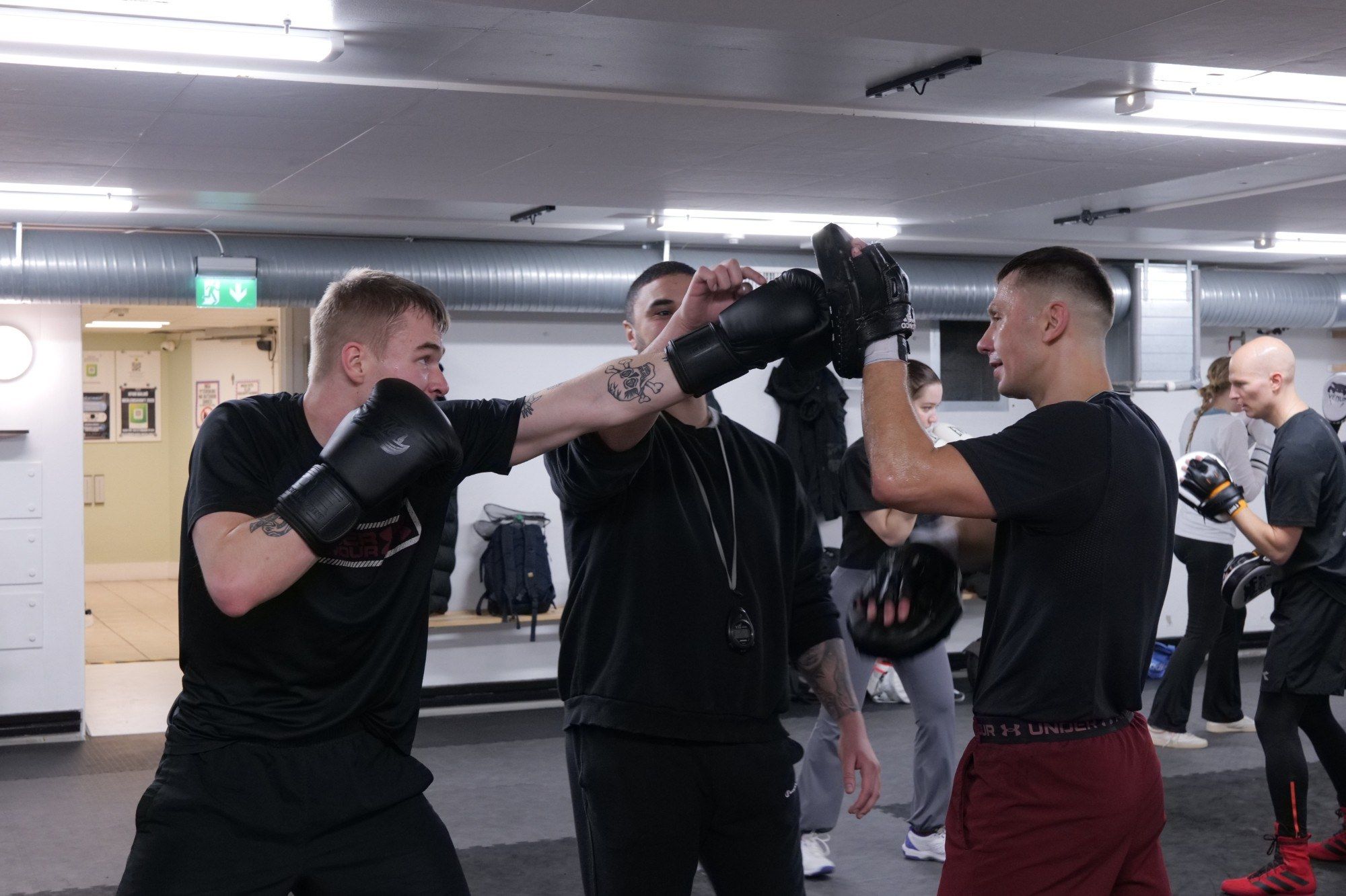 Coach correcting a straight punch on the pads during Fundamentals