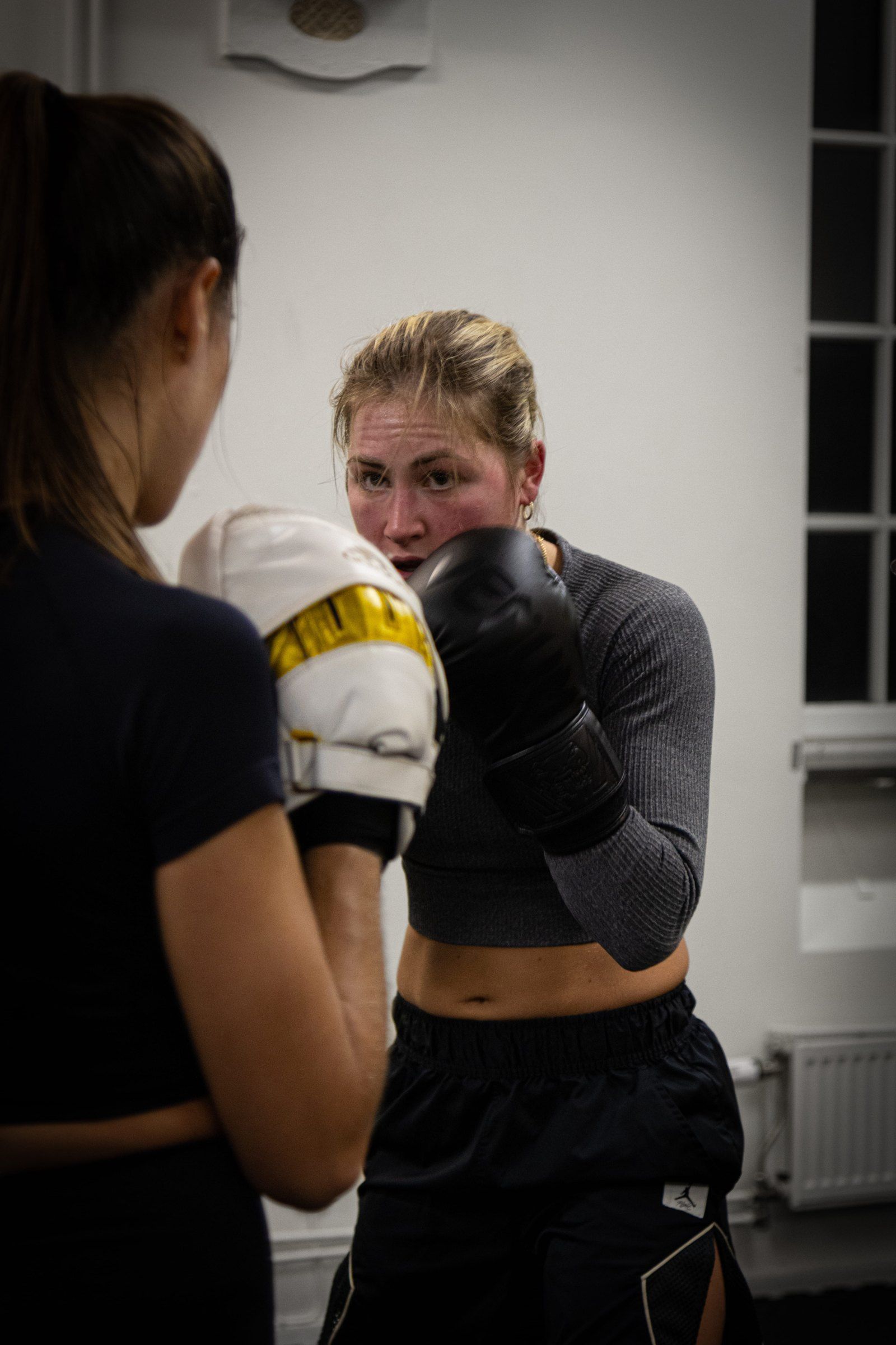 Two women training punches on pads